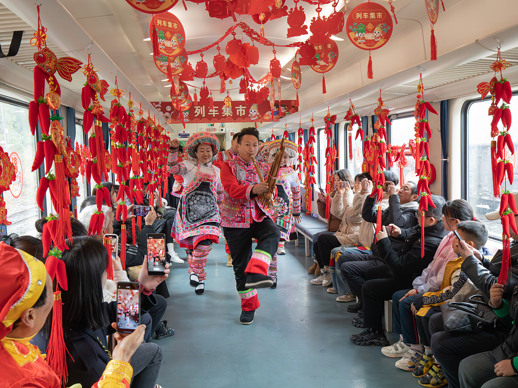 Passengers take photos of a folk culture show onboard a train departing from Zunyi, southwest China's Guizhou Province on February 23, 2024. /CFP