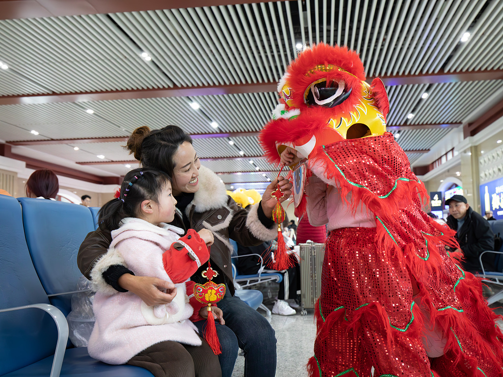 Passengers interact with a folk culture show performer while they wait for a train departing from Zunyi, southwest China's Guizhou Province on February 23, 2024. /CFP