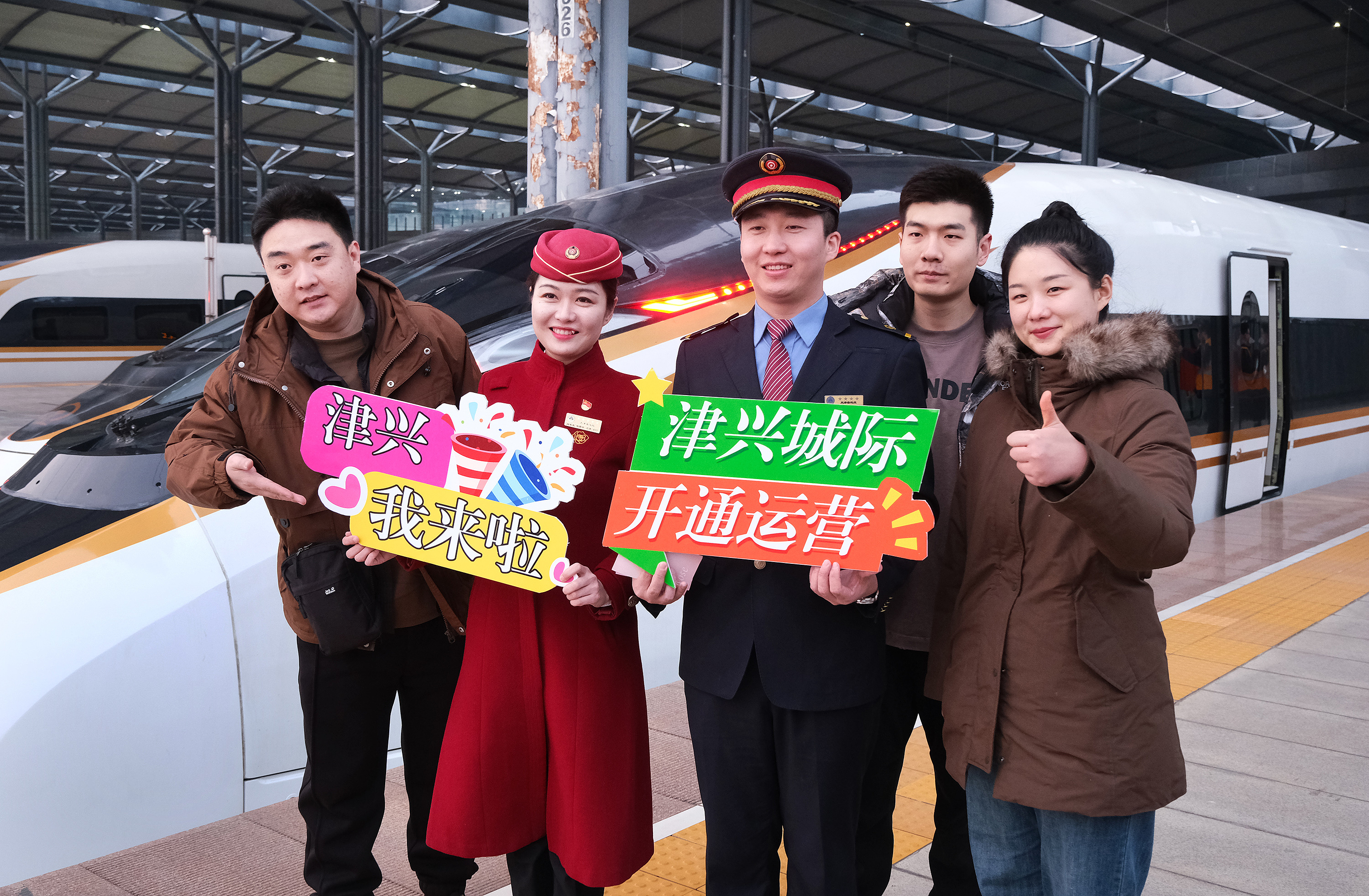 Passengers and crew members pose for a group photo outside a train at the Tianjin West Railway Station in Tianjin, north China, marking the opening of a new line connecting Tianjin with the Beijing Daxing International Airport, December 18, 2023. /CFP