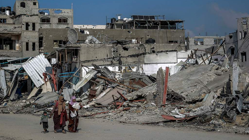 Palestinians walk past buildings destroyed during Israeli strikes in Beit Lahia in northern Gaza, on February 26, 2024, amid continuing battles between Israel and the Palestinian militant group Hamas. /CFP