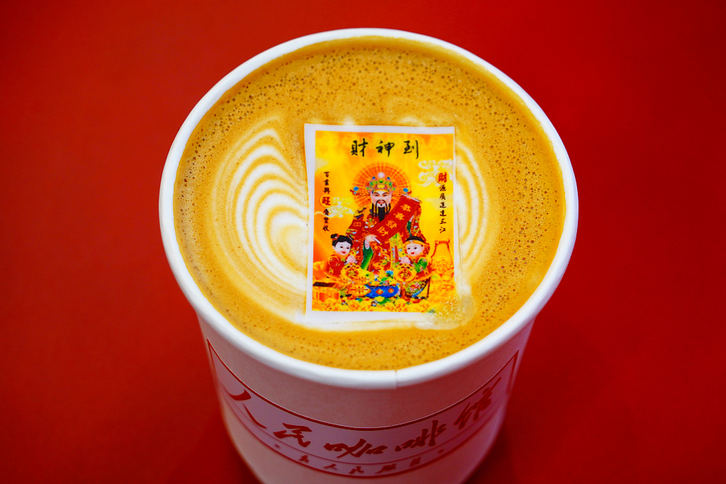 A cup of coffee with a picture of the God of Wealth on its top is seen at a coffee shop in Beijing on February 26, 2024. /CFP