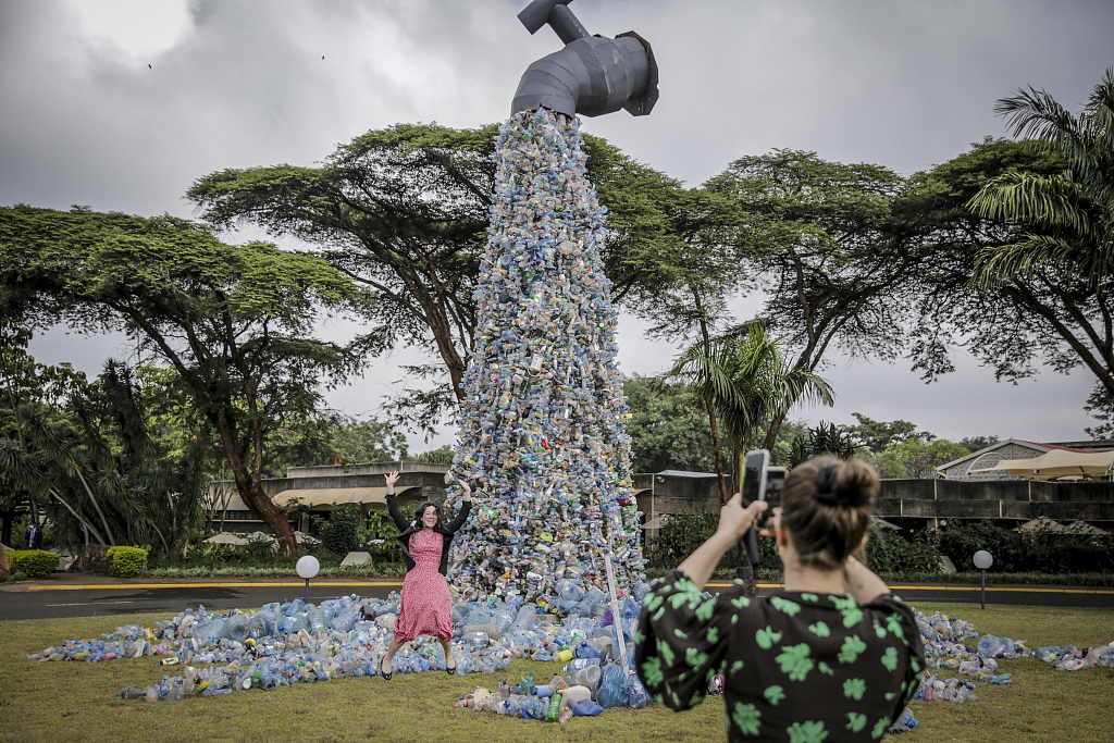 People take photos of themselves in front of a giant art sculpture showing a tap outpouring plastic bottles, each of which was picked up in the neighborhood of Kibera, at the United Nations Environment Program headquarters in Nairobi, Kenya, March 2, 2022. /CFP
