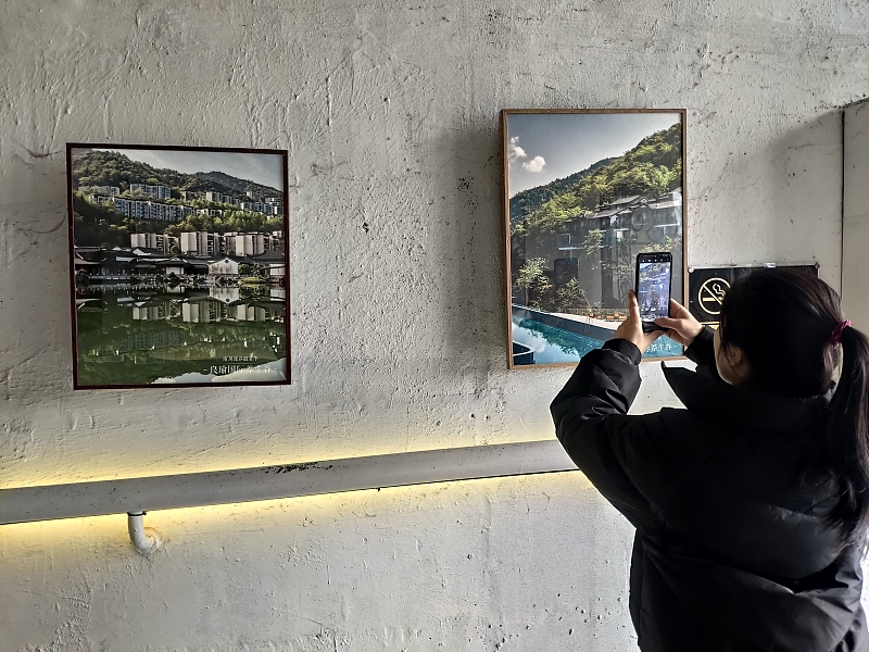 A visitor takes photos of paintings at an art space in Chongqing, February 27, 2024. /CFP