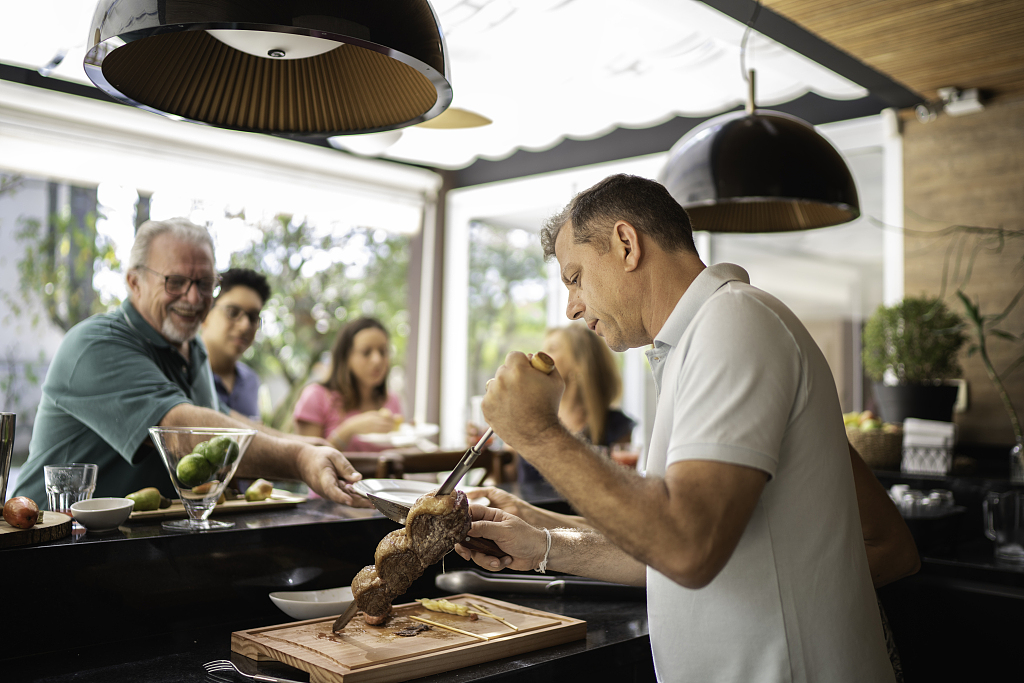 A photo shows a waiter slicing meat from a skewer to serve guests in a Brazilian churrascaria. /CFP
