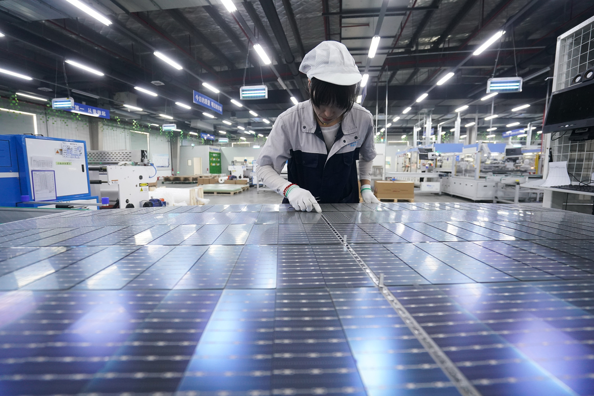 An employee checks photovoltaic panels at a production facility in Suqian, China's Jiangsu Province. /Xinhua
