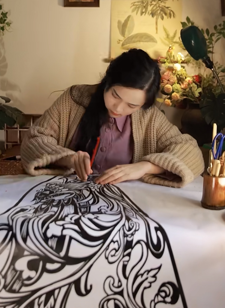 Chen Lingling makes paper-cut patterns for her cloak. /Screenshot from Xiaohongshu