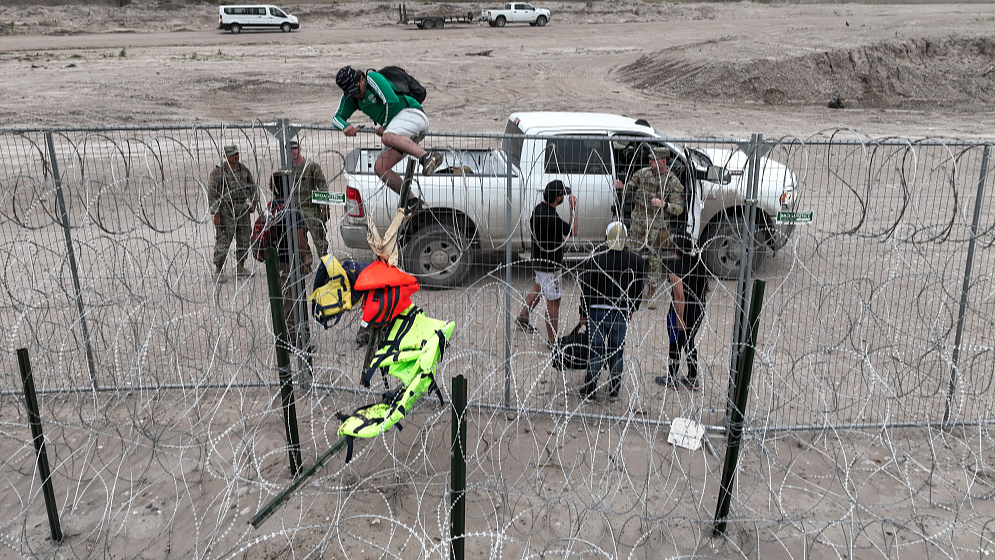 An aerial view shows a group of migrants illegally climbing up wire fences at the border despite the heightened security in Eagle Pass, Texas, U.S., February 28, 2024. /CFP
