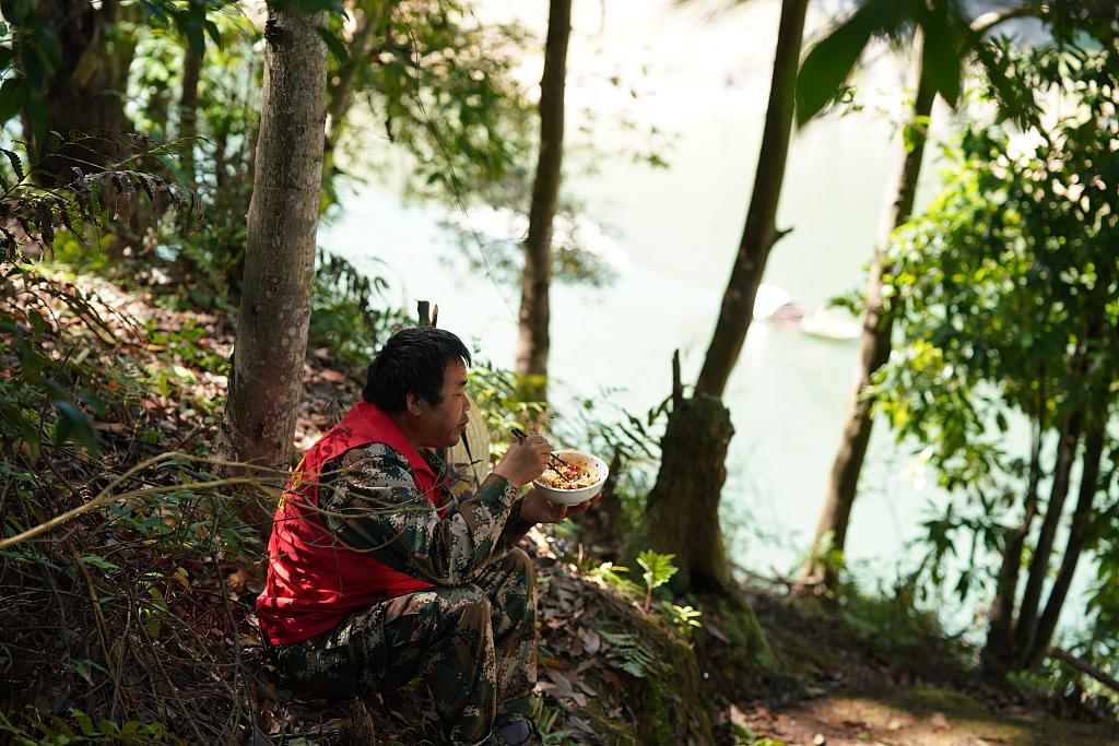 Forest ranger Yang Xingpu eats lunch in the mountain at the reservoir area of Shaikou Hydropower Station in the Yudaihe National Wetland Park in Tongdao Dong Autonomous County, central China's Hunan Province, October 15, 2023. /CFP