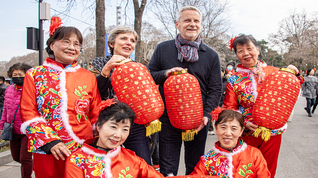 Foreign tourists pose with red lanterns and performers at a park in Nanjing City, east China's Jiangsu Province, February 13, 2024. /CFP
