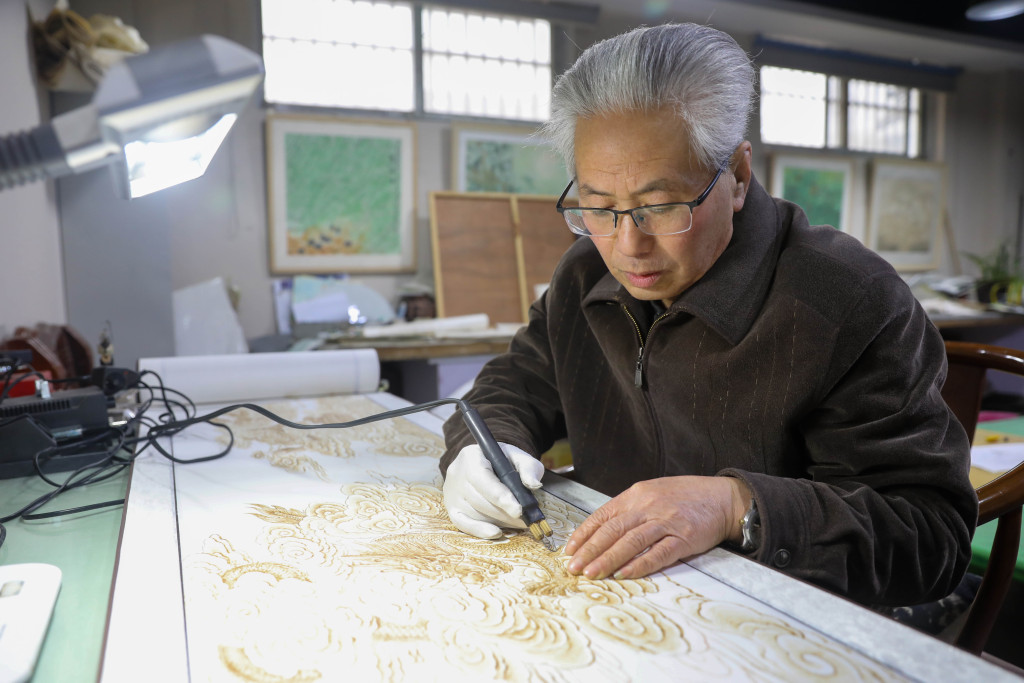 Artist Wang Fuyong works on a dragon-themed pyrography work in Pingdingshan, Henan Province, January 31, 2024. /CFP