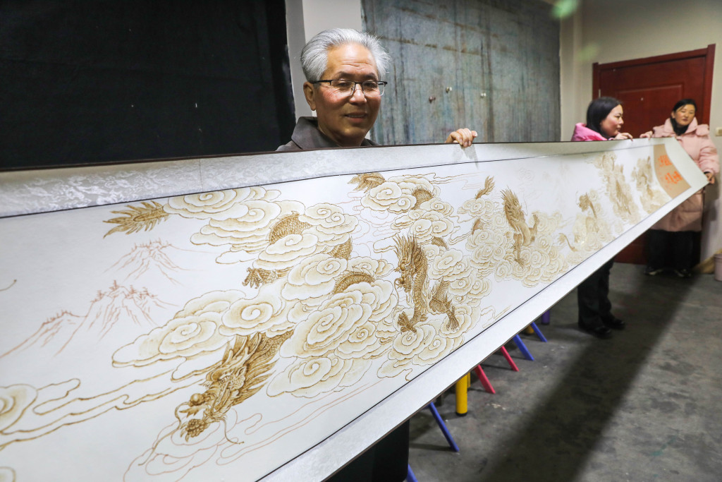 Pyrography artist Wang Fuyong holds up his dragon-themed scroll in Pingdingshan, Henan Province, January 31, 2024. /CFP