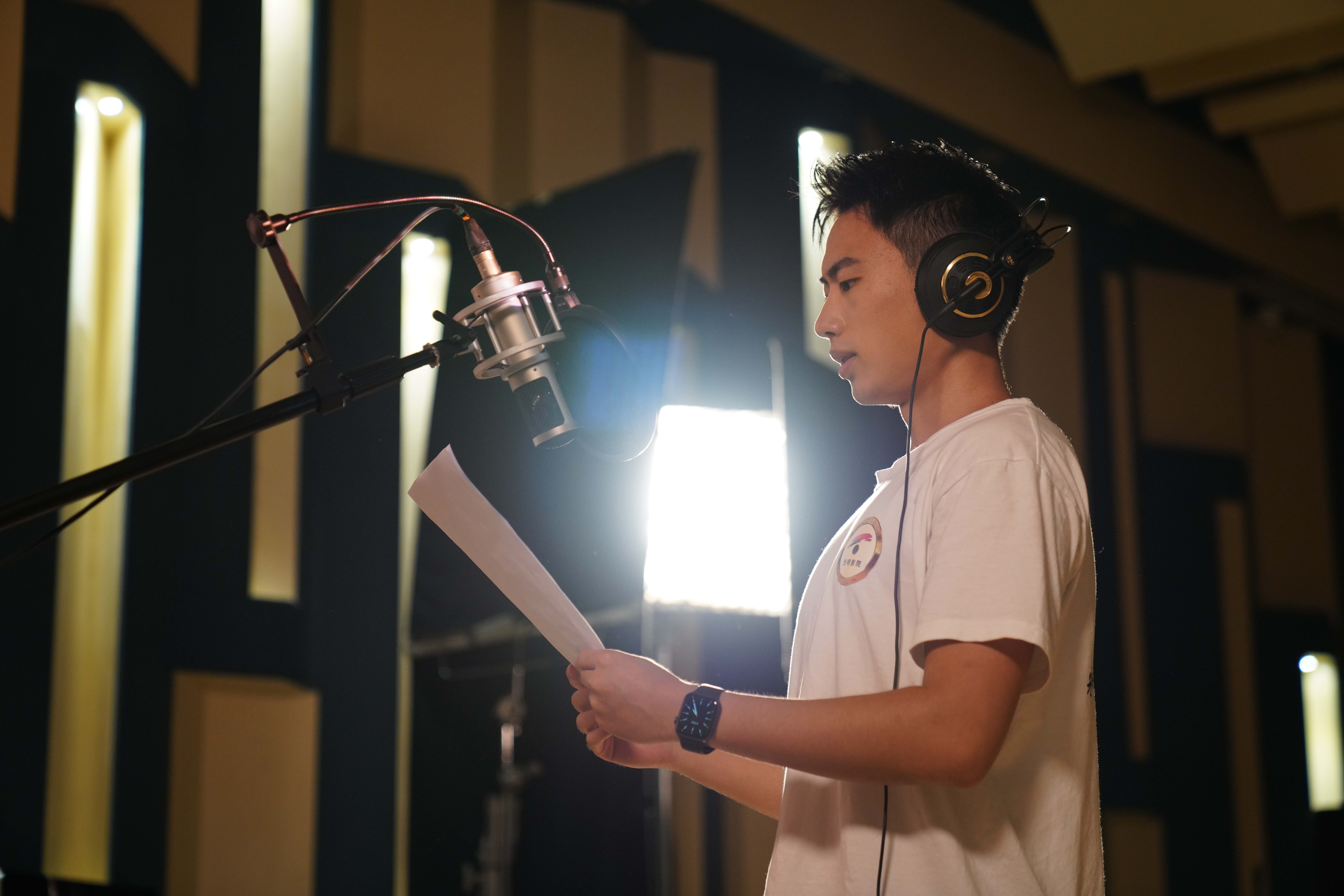 A file photo shows student volunteer Chen Zhongrui dubbing a narration in a recording studio. /Photo provided to CGTN