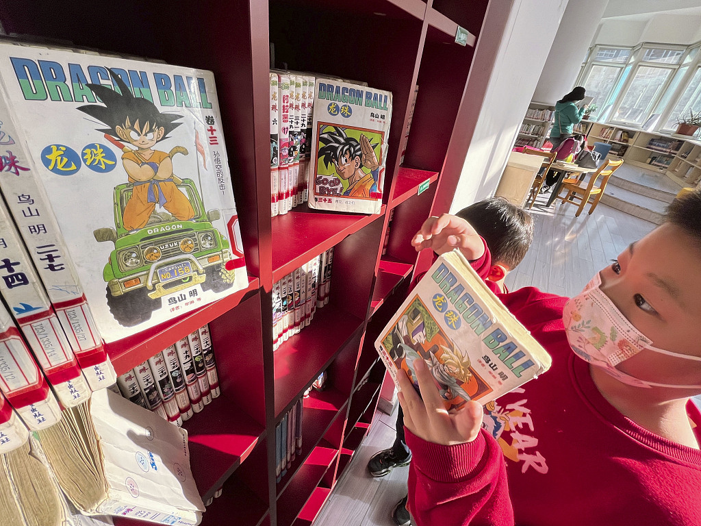 A photo taken on March 8, 2024 shows a child picking up a Chinese version of the Japanese manga 