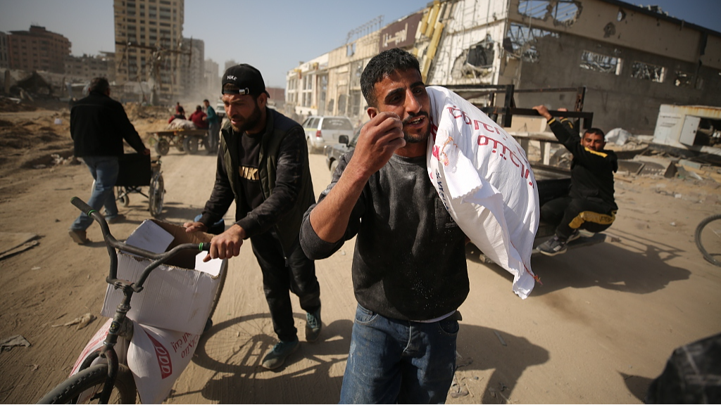Palestinians, who are unable to meet their basic needs due to Israel's obstruction of humanitarian aid, receive a bag of flour from an aid truck that arrived in the west of Gaza City, March 6, 2024. /CFP
