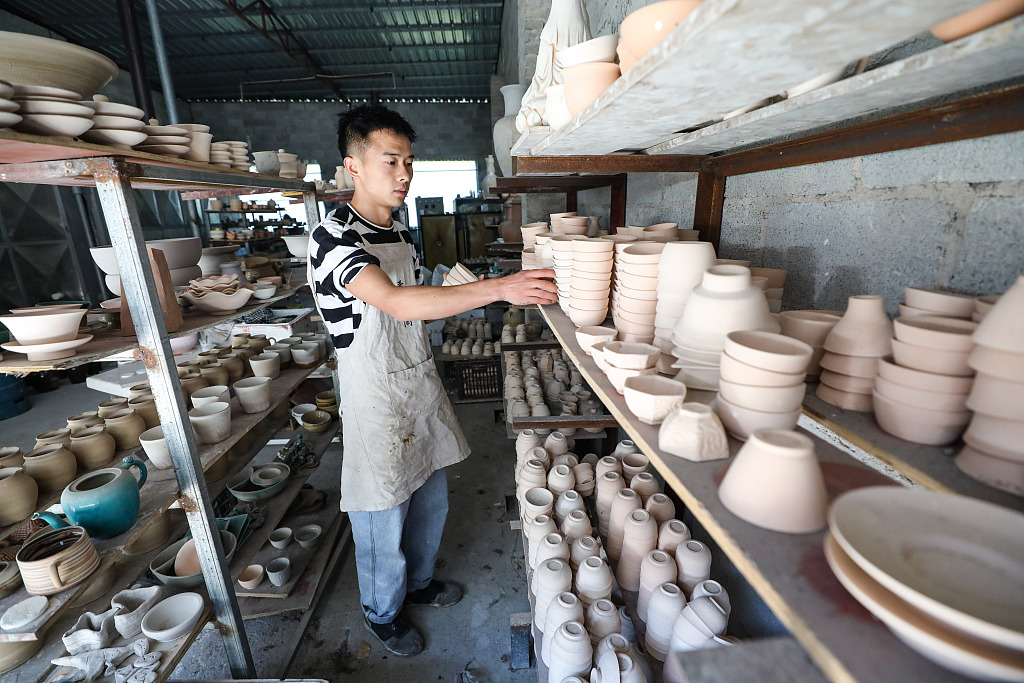 A file photo shows Zhang Shengbo sorting pottery items in Yazhou Town, Guizhou Province. /CFP