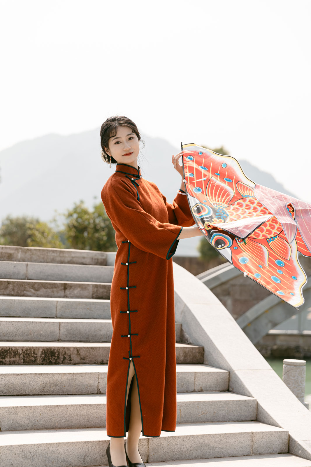 A woman dressed in a qipao poses for photos on a bridge at Yongquan Town in Linhai City, Zhejiang Province on March 7, 2024. /Photo provided to CGTN by the Government of Yongquan Town