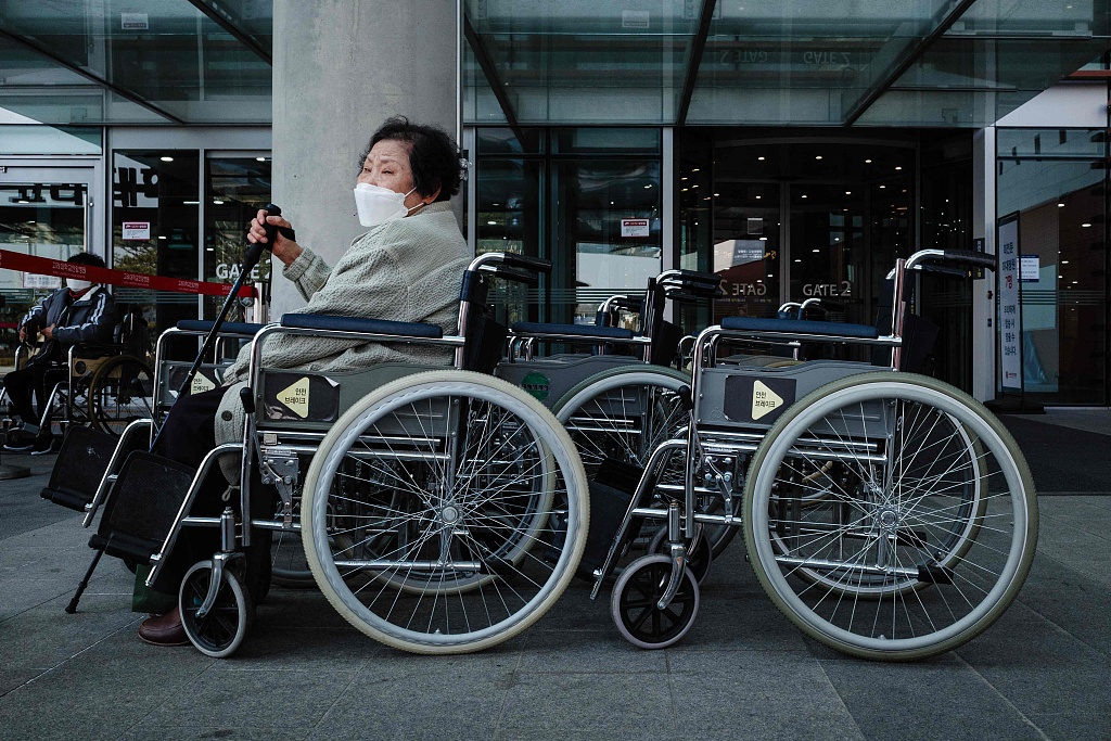An elderly woman waits in a wheelchair outside a hospital in Seoul, March 14, 2024. /CFP