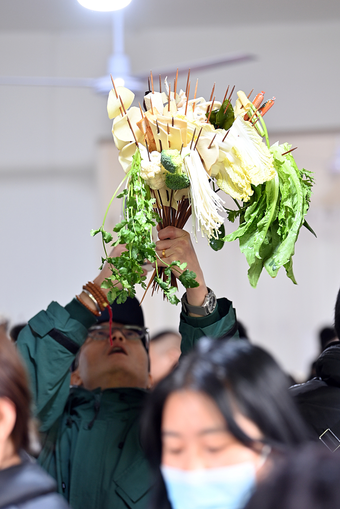 A photo taken on March 14, 2024 shows a customer holding a bunch of food ingredients for Tianshui spicy hot pot in Gansu Province. /CFP