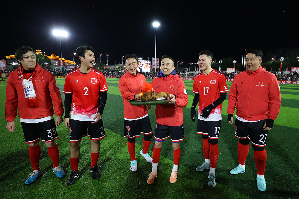 Footballers of a team from China's Macao Special Special Administrative Region receive a roasted pig as a gift after their match in the Village Super League in Rongjiang, China, February 3, 2024. /CFP 