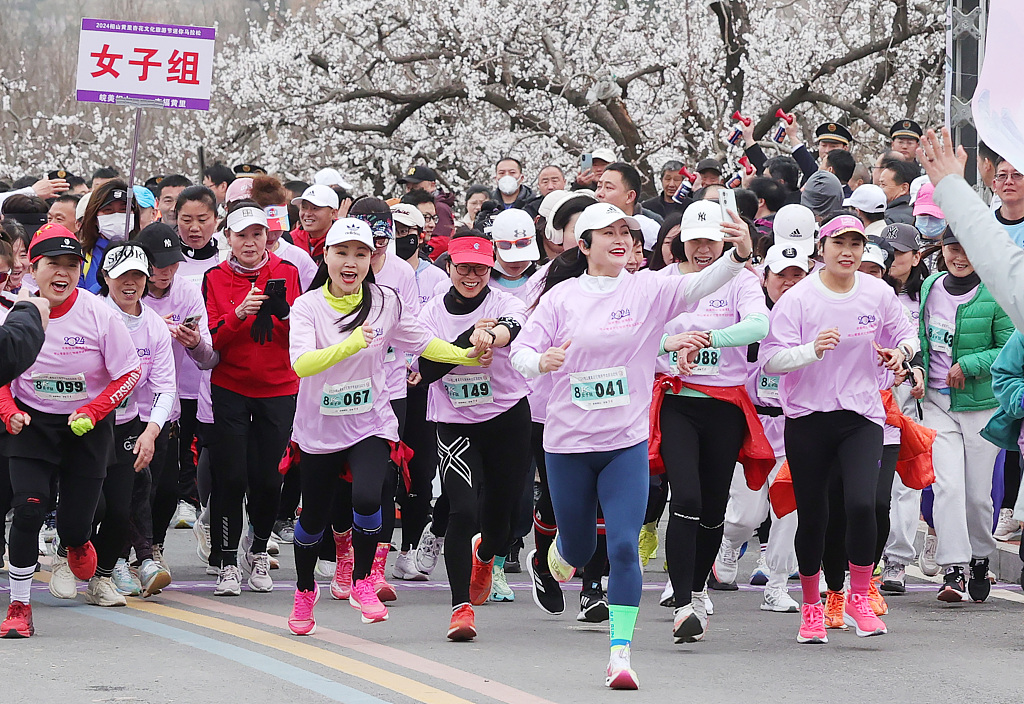 Female runners participate in a mini marathon along a road filled with blossoming apricot flowers in Huaibei, east China's Anhui Province, March 17, 2024. /CFP
