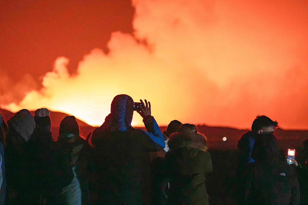 People gather to watch as molten lava flows out from a fissure on the Reykjanes peninsula north of the evacuated town of Grindavik, western Iceland, March 16, 2024. /CFP
