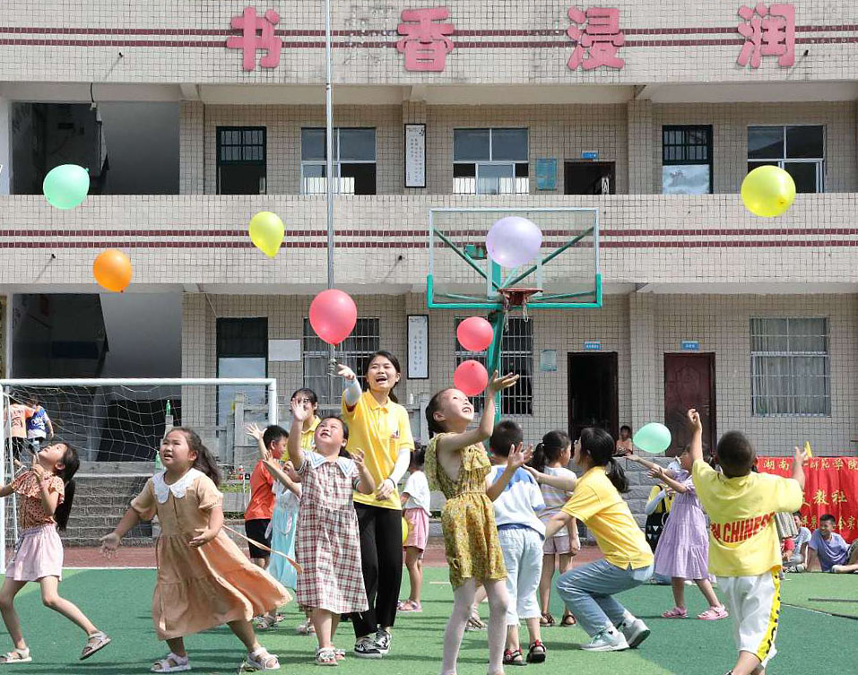 Student volunteers from Hunan First Normal University play with children at a school in Baojing County, Hunan Province on July 18, 2021. /CFP