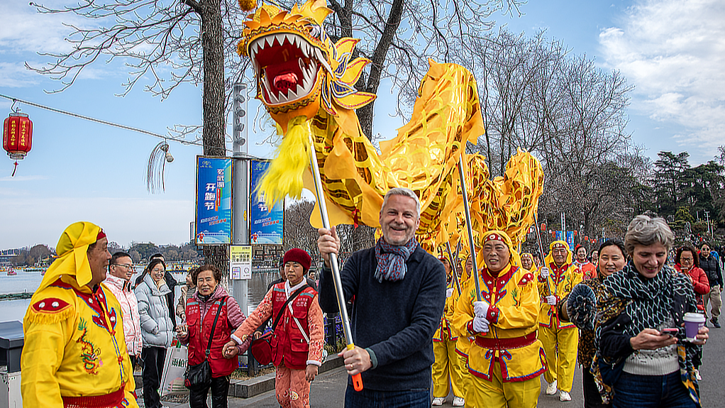 A foreign tourist takes part in a Chinese traditional dragon dance in Nanjing, east China's Jiangsu Province, February 13, 2024. /CFP