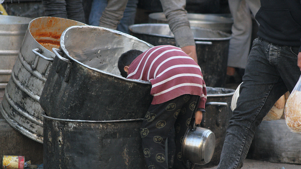 A Palestinian child searches for food scraps at a street kitchen in Deir al-Balah, central Gaza, March 19, 2024. /CFP