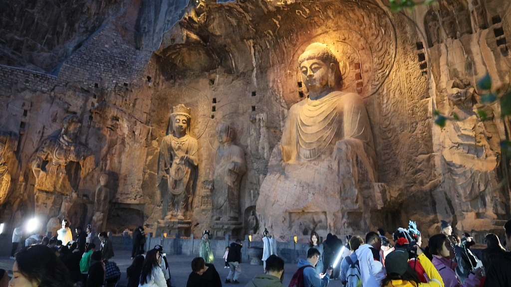 A photo taken on March 20, 2024 shows tourists visiting the Longmen Grottoes at night in Luoyang, Henan Province. /CFP