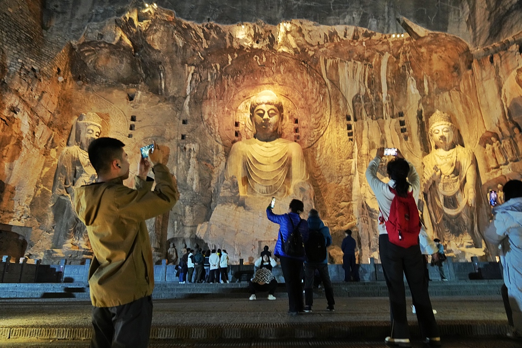 A photo taken on March 20, 2024 shows tourists visiting the Longmen Grottoes at night in Luoyang, Henan Province. /CFP