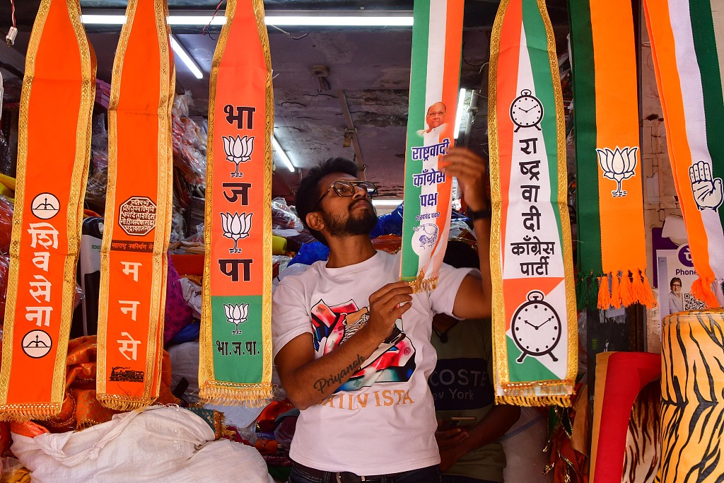 A man arranges scarves of political parties at a shop, ahead of Lok Sabha elections, Mumbai, India, March 20, 2024. /CFP