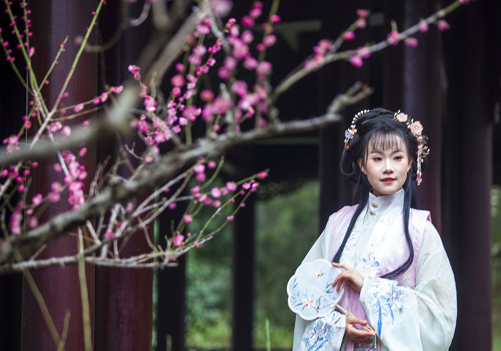 In this photo taken in March 2024, a hanfu enthusiast poses for a picture against a backdrop of flowers. /CFP
