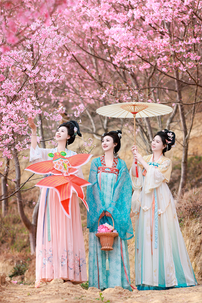 In this photo taken in March 2024, hanfu enthusiasts pose for a picture against a backdrop of flowers. /CFP