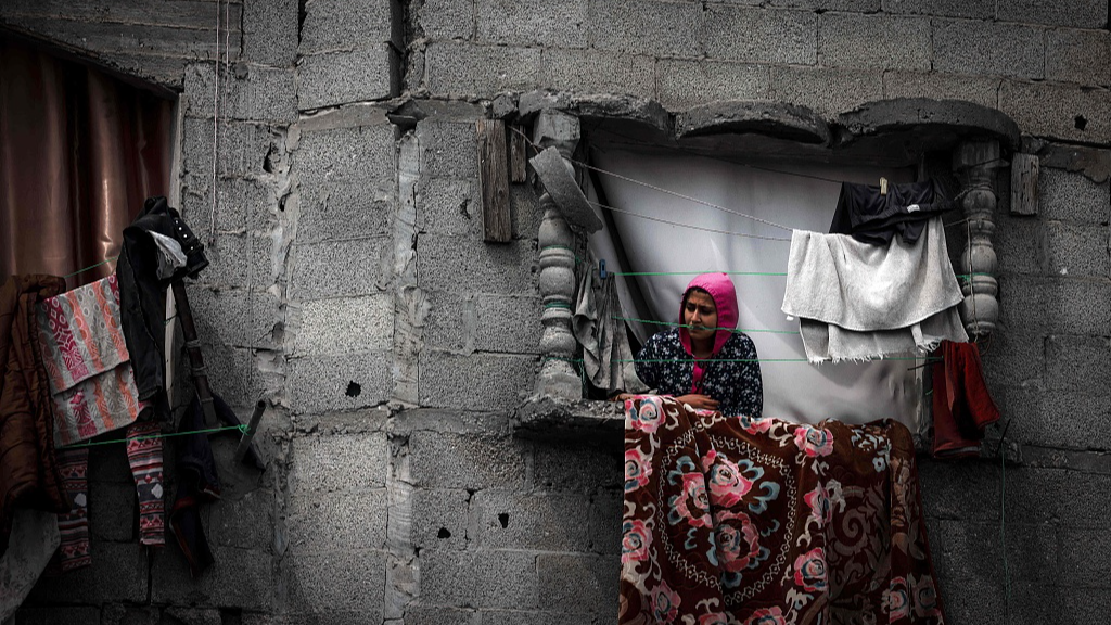 A Palestinian woman stands on the window of a building damaged by Israeli bombardment in Rafah in southern Gaza, March 22, 2024. /CFP