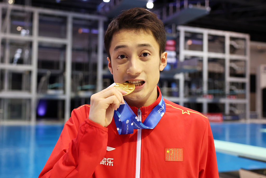 China's Lian Junjie bites his gold medal to celebrate after the men's 10m platform final during the Diving World Cup in Berlin, Germany, March 24, 2024. /CFP