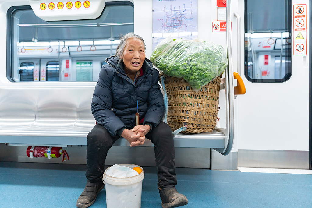 A file photo shows a farmer carrying a bamboo basket filled with vegetables on Chongqing’s subway Line 4. /CFP