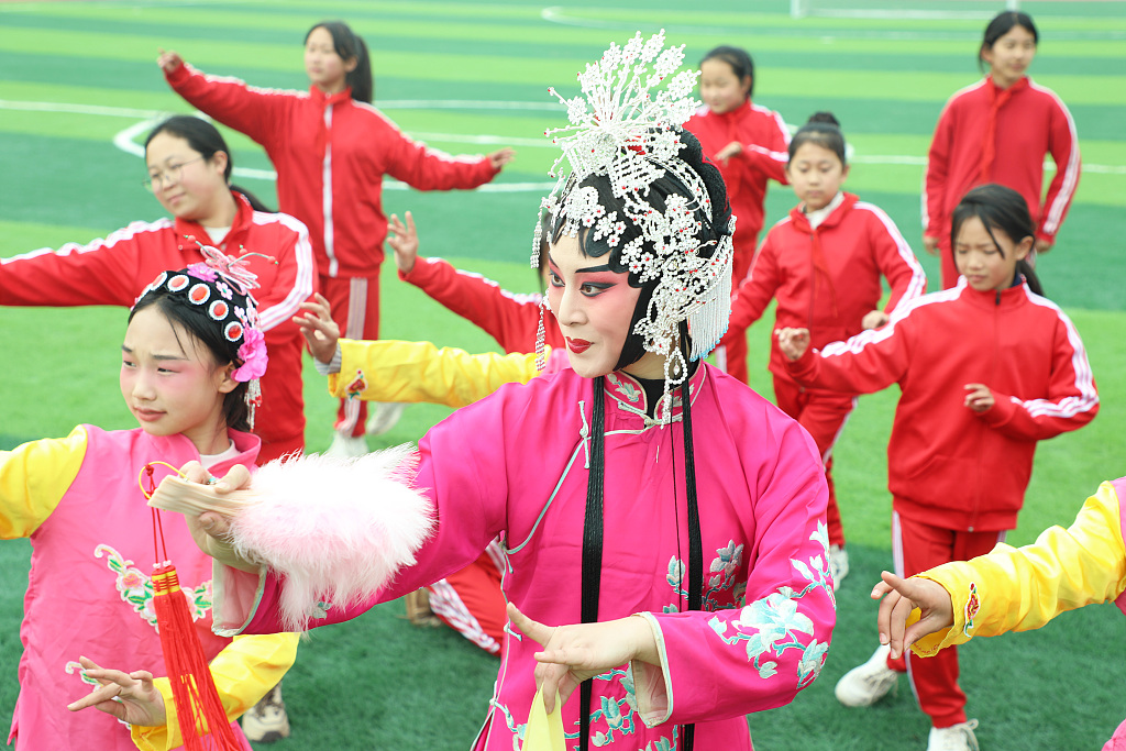 Pupils learn the moves from a professional Pingju Opera at an elementary school in Tangshan, Hebei Province, March 26, 2024. /CFP
