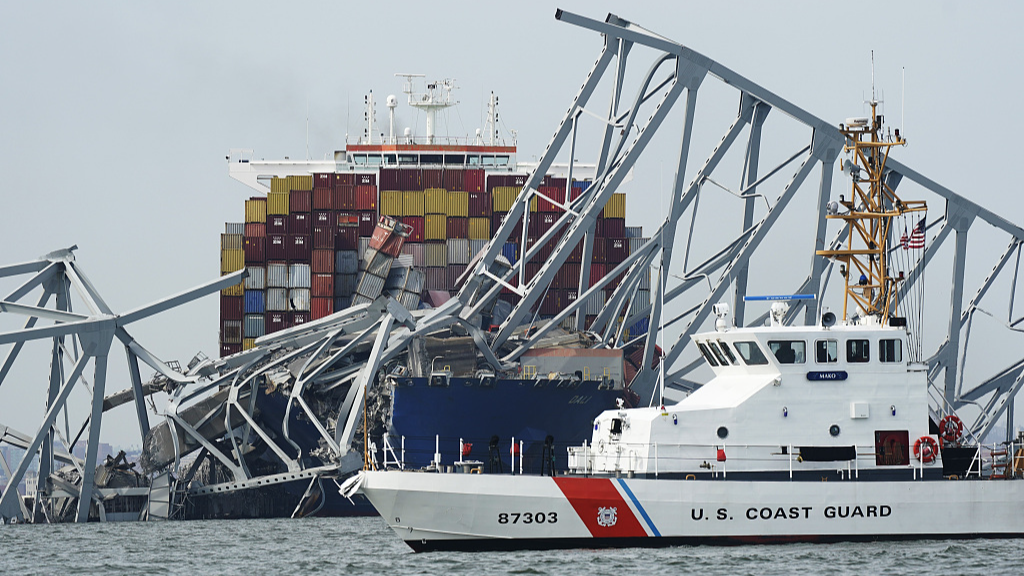 A U.S. Coast Guard cutter passes a cargo ship that is stuck under the part of the structure of the Francis Scott Key Bridge after the ship hit the bridge  in Baltimore, Maryland, U.S., March 26, 2024. /CFP