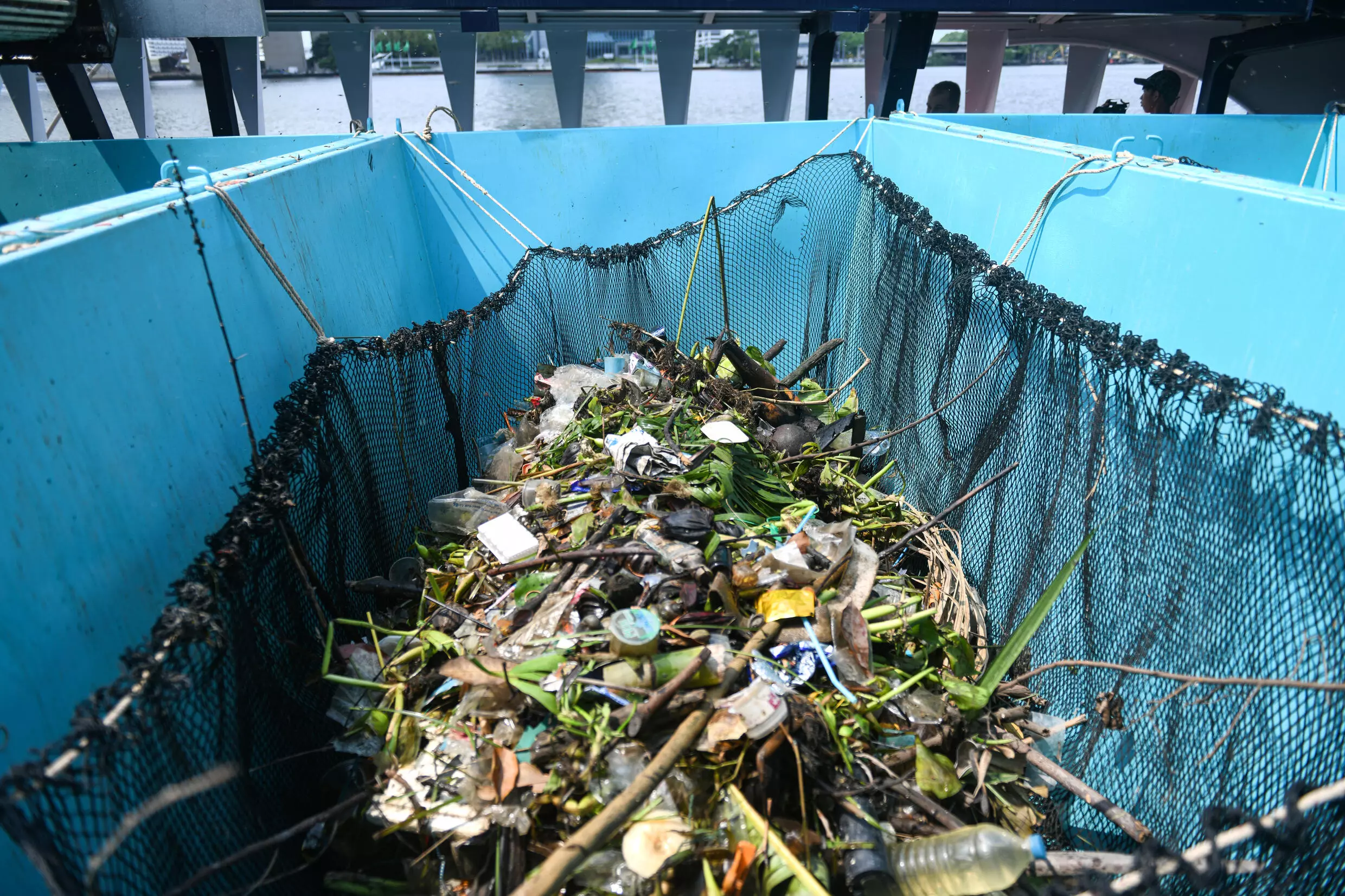 Ticking bamboo-slatted treadmills carry the collected waste into the barge, where it is deposited into bright blue skips and taken ashore to be disposed of by local authorities in Bangkok, Thailand. /AFP