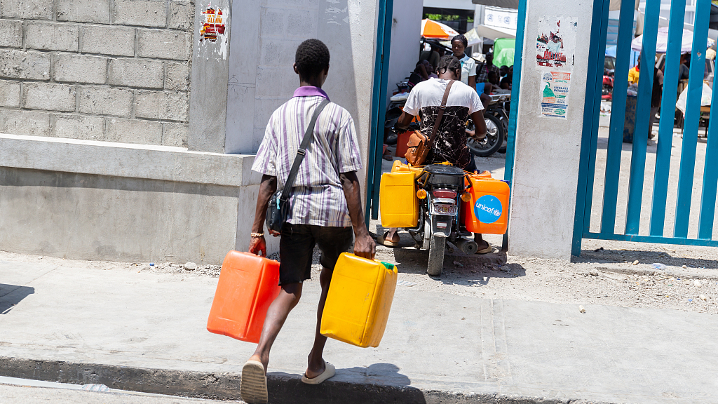 Men enter with gallons of water in their temporary shelters on the Rue de Port-au-Prince, against the backdrop of continuing insecurity and political instability in Port-au-Prince, Haiti, March 22, 2024. /CFP