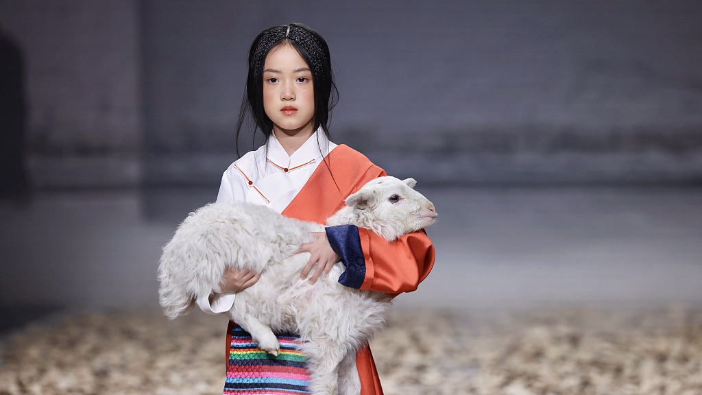 A young model holding a lamb walks the runway at the SUBAI collection show by designer Ma Guai at AW24 China Fashion Week in Beijing on March 26, 2024. /CFP