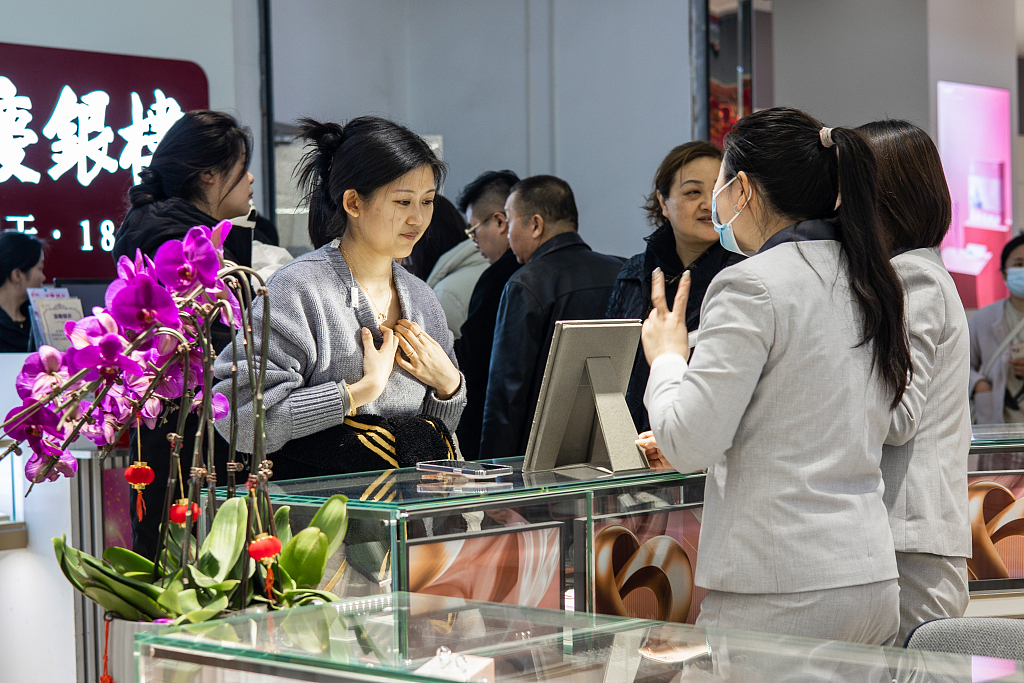 Customers try on jewelry in a shopping mall in Nanjing, east China's Jiangsu Province, March 8, 2024. /CFP