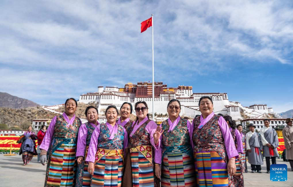 People pose for photos after a flag-raising ceremony to celebrate Serfs' Emancipation Day in front of the Potala Palace in Lhasa, capital of southwest China's Xizang Autonomous Region, March 28, 2024./Xinhua