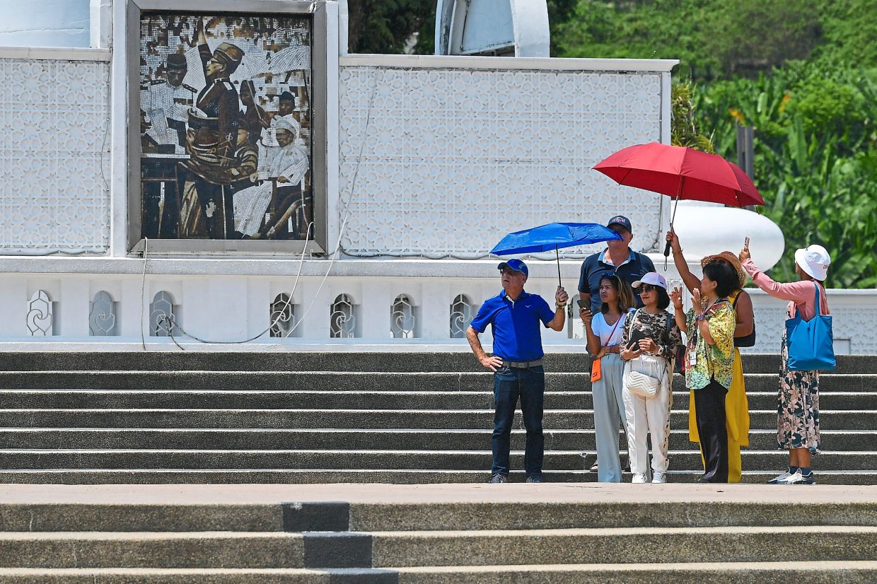 Tourists visiting Dataran Merdeka use umbrellas to seek refuge from the scorching heat that is currently hitting the country, Kuala Lumpur, Malaysia, March 24, 2024. /Reuters