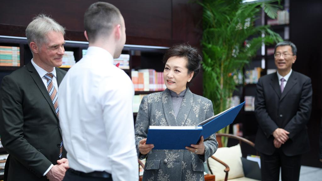 Peng Liyuan, the wife of Chinese President Xi Jinping, receives a photo album documenting her friendly exchanges with the Chinese Choir of the Burg Gymnasium in the past decade, from a student representative of the choir at Beijing No.35 High School in Beijing, China, March 28, 2024. /Xinhua