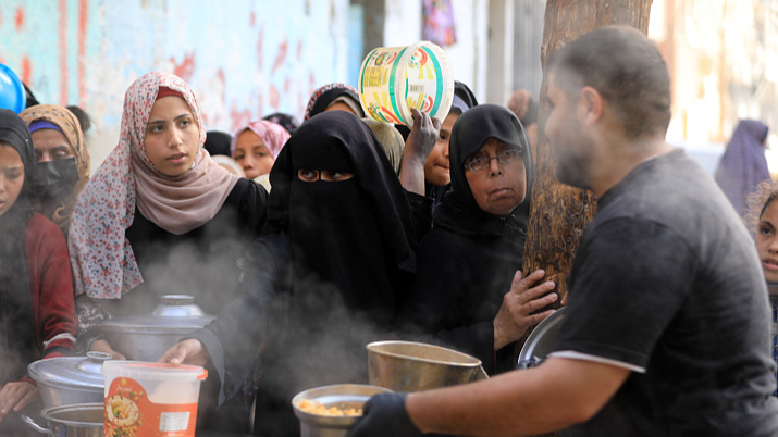 Palestinians hold empty containers to receive food, distributed by aid organizations, on the holy month of Ramadan in Rafah, Gaza, March 30, 2024. /CFP