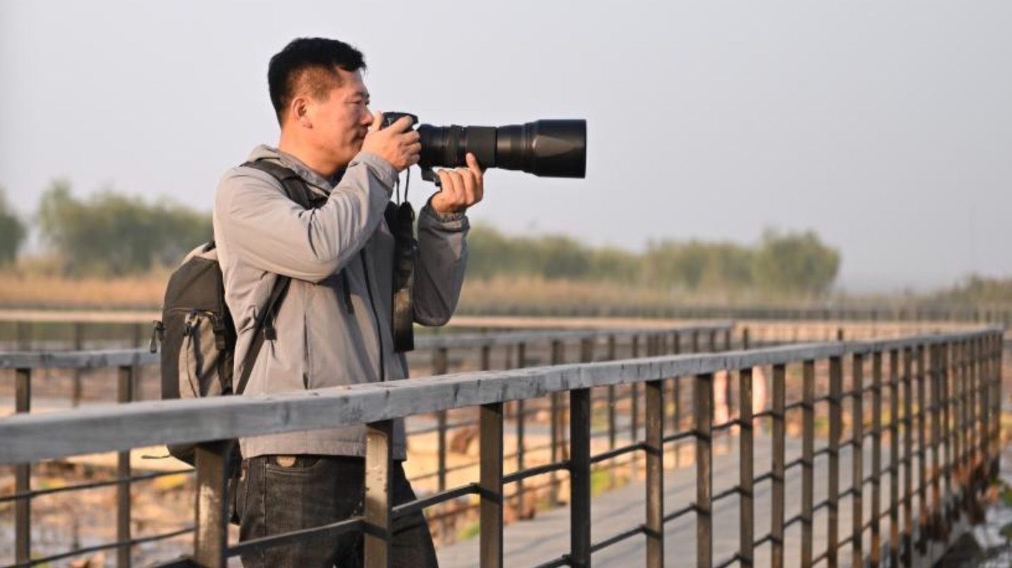 Han Zhanqiao photographs wild birds in Xiong'an New Area, north China's Hebei Province, October 24, 2024. /Xinhua