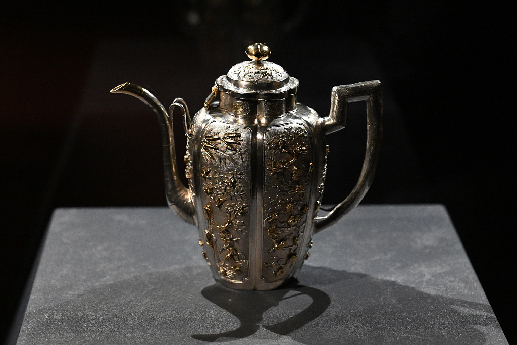Gilding with gold flowers peonies, birds, butterflies and pagodas, the jug features a handle and long spout that resemble wood and bamboo. /CFP