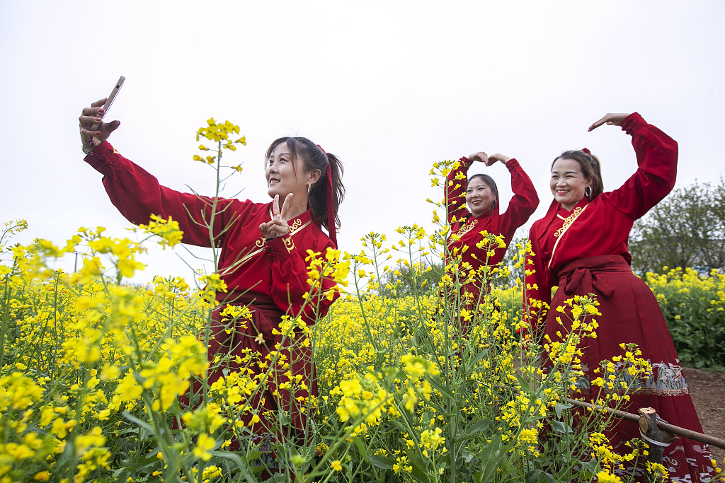 Visitors take photos among blooming rapeseed flowers in Jiaozuo, Henan Province on April 4, 2024, as they enjoy the Qingming Festival holidays. /CFP