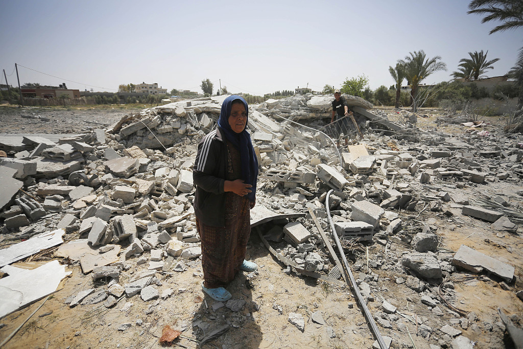 A view of a destroyed building as a Palestinian woman looks on at the Nuseirat refugee camp after an Israeli airstrike in Deir Al Balah, Gaza, April 5, 2024. /CFP